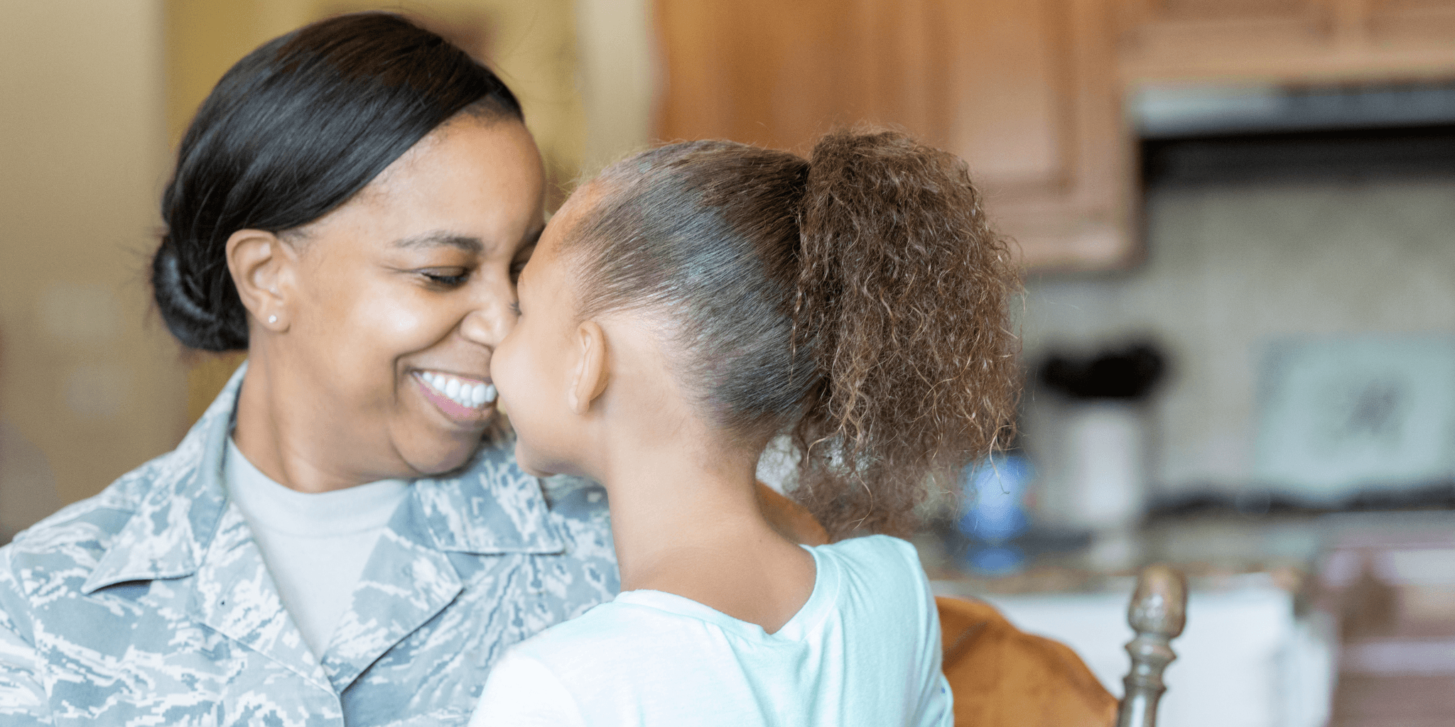 A smiling service member sharing a warm moment with her daughter at home