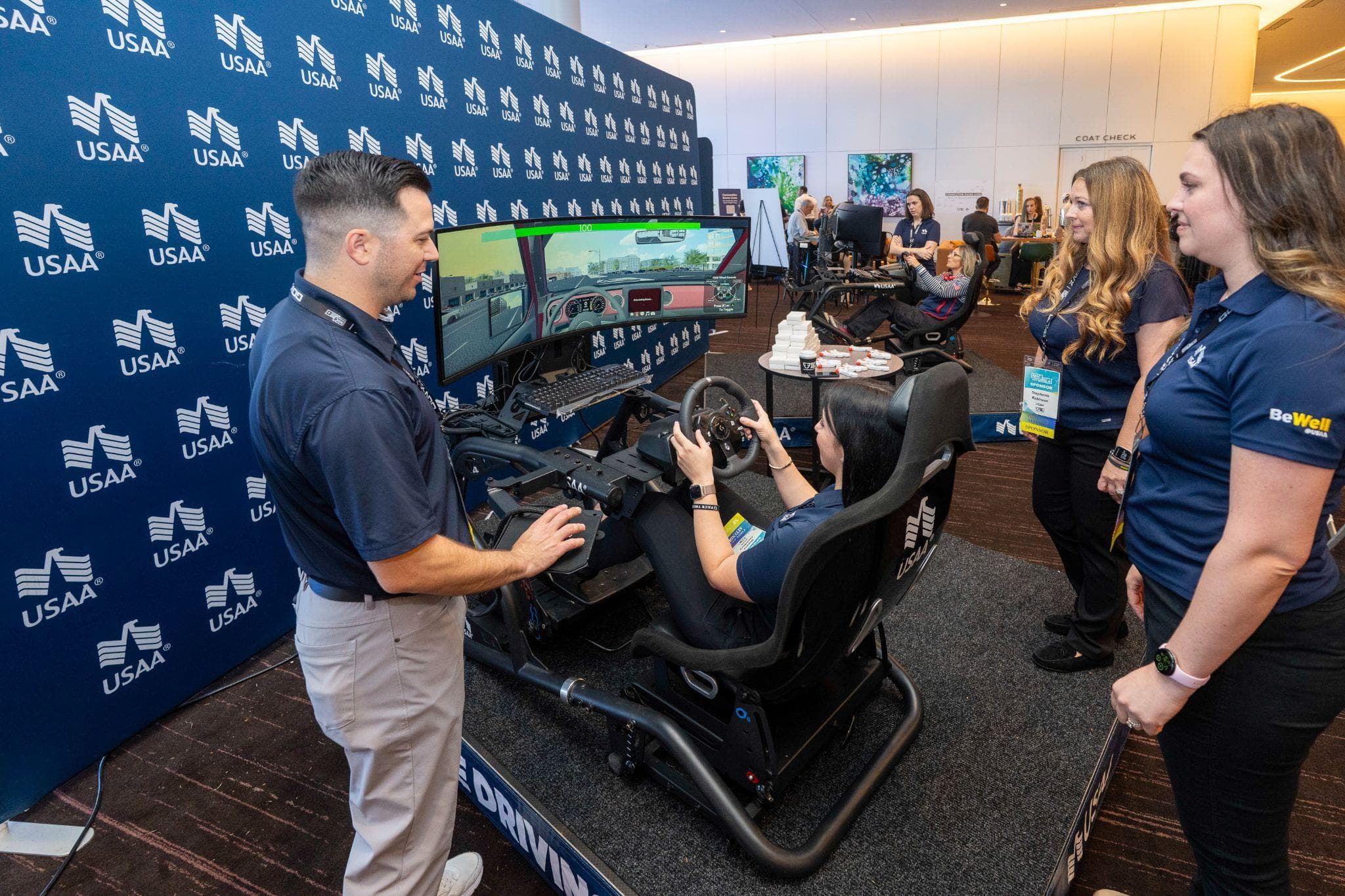 Attendees engage with a driving simulator activation at a Military Impact Conference exhibitor booth